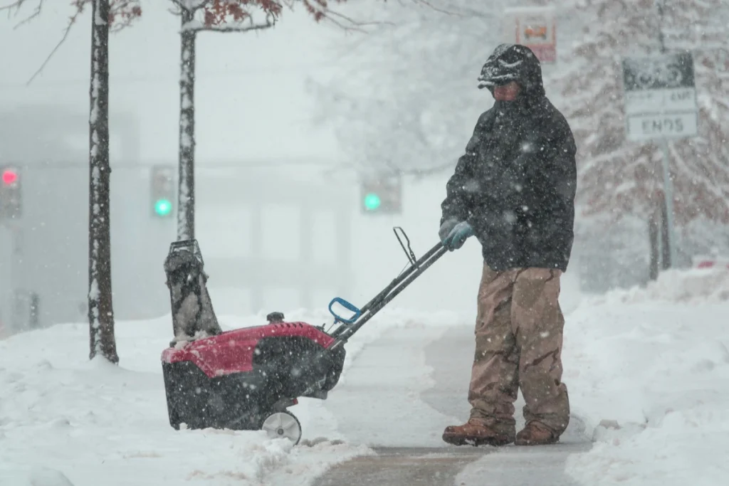 Man Clearing Snow from an Icey Sidewalk