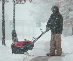 Man Clearing Snow from an Icey Sidewalk